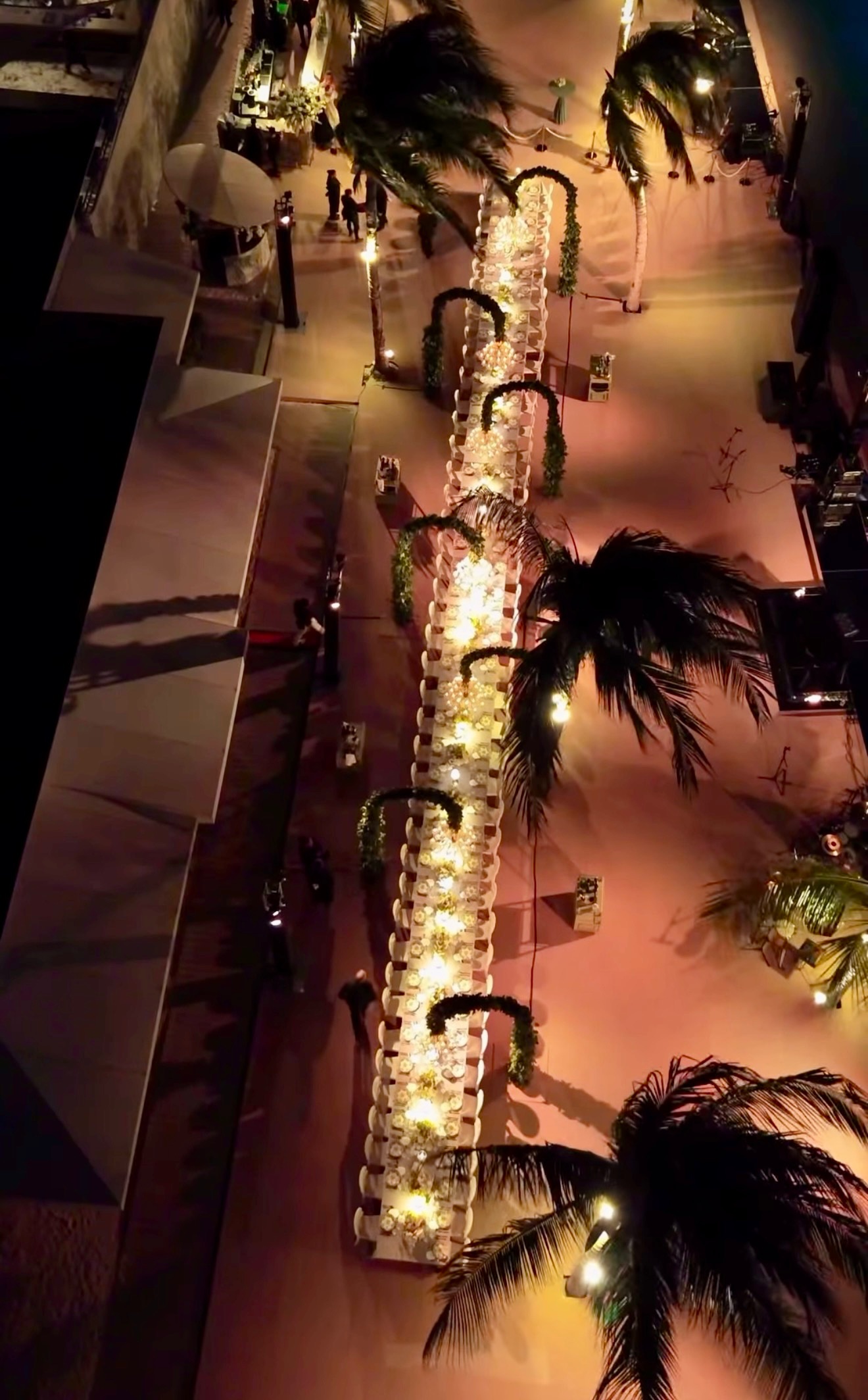 Dronefoto van bruiloft verlichting huren op Curacao: kristallen kroonluchters aan bogen boven een lange dinertafel tussen de palmen