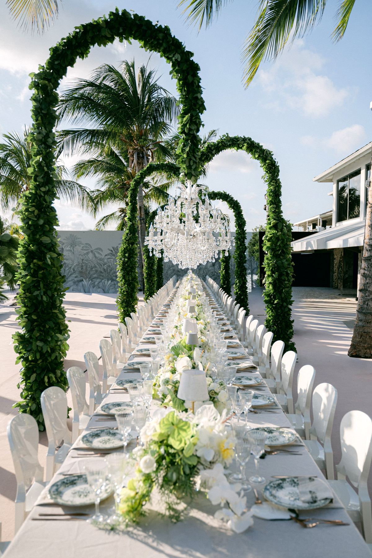 Volledige dinertafel onder groene bogen met kristallen kroonluchter, strandbruiloft Curacao