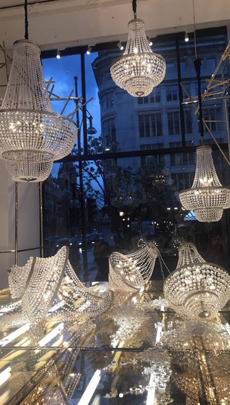 Etalage van Selfridges London met drie hangende kristallen kroonluchters en neon-logo